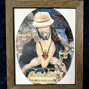 May include: A framed collage of a religious figure wearing a white fur hat and a gold chain with a red heart pendant. The figure is holding a vintage cell phone to their ear. The background is a collage of various textures and patterns.