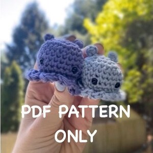 May include: Two crocheted octopus amigurumi toys in shades of purple and blue. The toys are held in a hand with the text "PDF PATTERN ONLY" below them.
