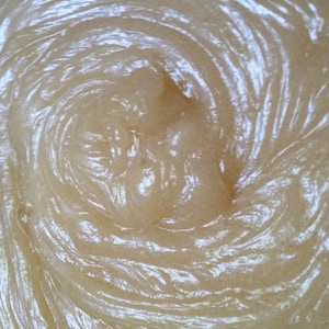 May include: A close-up of a light brown, creamy substance with a swirling pattern. The substance appears to be thick and viscous.