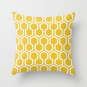 May include: Square throw pillow with a repeating geometric pattern of white and yellow honeycomb shapes. The pillow has a solid yellow background with a white outline of the honeycomb design.
