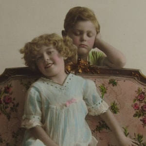 Sweet vintage postcard of a little girl sitting on the sofa and a sleeping boy behind her!  Old postcard, antique postcard children