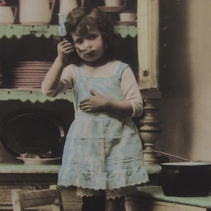 Old postcard of a cute little girl who is helping a bit in the kitchen, vintage postcard, antique postcard