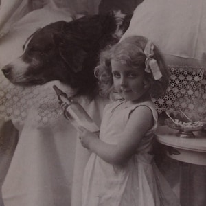 Glossy vintage postcard of a little girl with a drink and a cookie and her dog