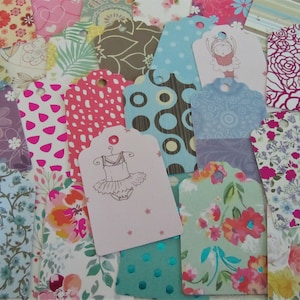 Op de afbeelding: Assortiment van kleurrijke cadeau-etiketten met verschillende ontwerpen, waaronder bloemen, stippen en geometrische patronen. Sommige etiketten bevatten illustraties van een ballerina en een bloem.