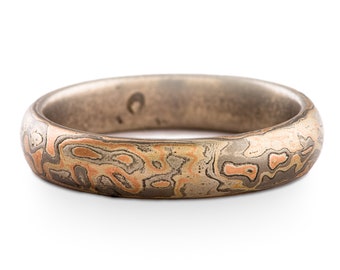 May include: A wide band ring with a unique marbled pattern in shades of brown, gray, and copper.