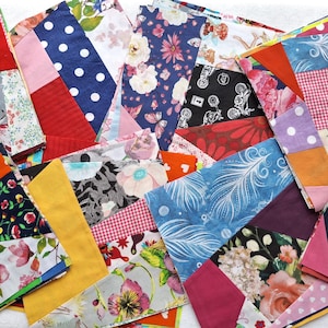 Può includere: Primo piano di un design patchwork realizzato con varie toppe di tessuto. Le toppe presentano diversi motivi come pois, disegni floreali e forme geometriche. La tavolozza dei colori comprende rosso, blu, rosa, giallo e arancione.