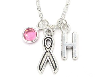May include: Silver chain necklace with a pink crystal, a silver ribbon charm, and a silver letter H charm.