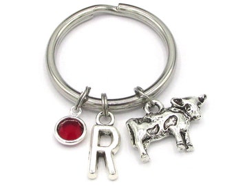 May include: Silver keychain with a cow charm, a red gem charm, and a letter 'R' charm.