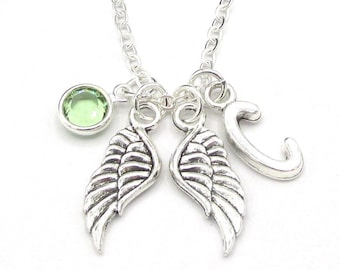 May include: Silver necklace with a green gemstone, two angel wing charms, and a letter 'C' charm.