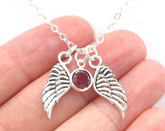 May include: Silver chain necklace with a pair of silver angel wings and a pink rhinestone in the center.