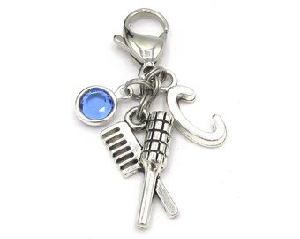 May include: Silver charm with a blue rhinestone, a comb, a hair roller, and the letter C. The charm is attached to a silver lobster clasp.