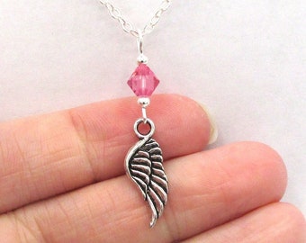 May include: A silver chain necklace with a single pink crystal and a silver wing charm.