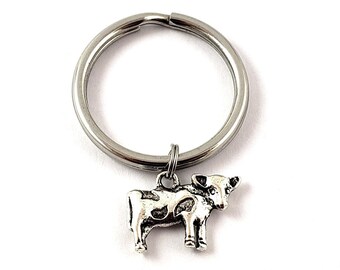 May include: A silver key chain with a small silver cow charm. The cow charm has black spots and a silver ring.