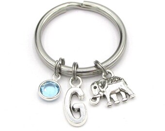 May include: A silver key chain with a blue crystal charm, a silver letter G charm, and a silver elephant charm.