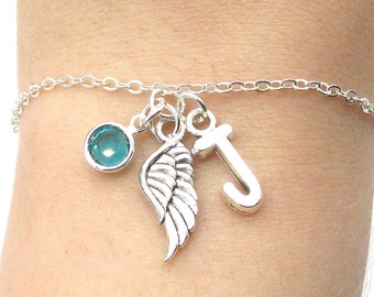 May include: A silver charm bracelet with a turquoise blue crystal, a silver wing charm, and a silver letter J charm.