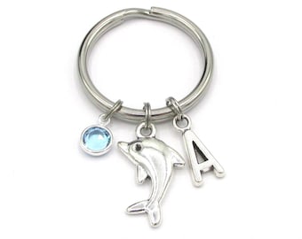May include: Silver key chain with a blue crystal charm, a silver dolphin charm, and a silver letter A charm.