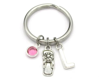 May include: A silver key chain with a pink rhinestone, a silver charm of a flip flop, and a silver charm of the letter L.