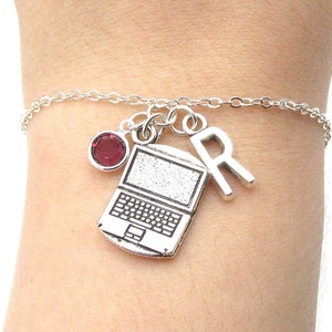 May include: A silver charm bracelet featuring a laptop, letter R, and a dark red gemstone charm.