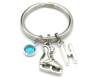 May include: Silver key chain with a blue crystal charm, a silver ice skate charm, and a silver charm with the letter H.