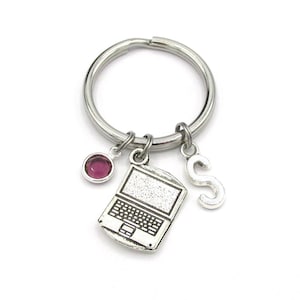 Peut inclure: Porte-clés argenté avec un charme d'ordinateur portable, un strass rose et un charme lettre 'S'.