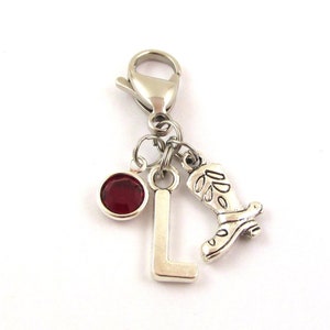 May include: Silver charm with a red rhinestone, a silver letter L, and a silver boot charm. The charm is attached to a silver lobster clasp.