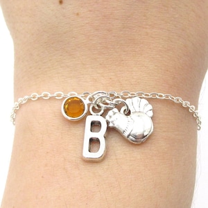 May include: A silver charm bracelet with a silver letter B charm, a silver turkey charm, and an amber-colored gemstone charm.