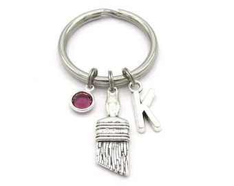 May include: Silver keychain with a paintbrush charm, a pink rhinestone charm, and a silver letter K charm.
