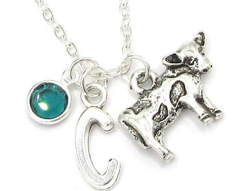 May include: Silver necklace with a cow charm, a letter C charm, and a teal blue gemstone.