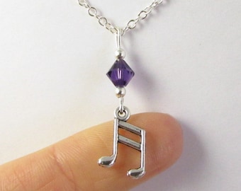 May include: A silver necklace with a music note charm and a purple crystal accent.