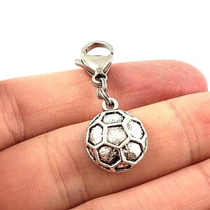 May include: Silver charm featuring a football design. The charm has a silver chain and a lobster clasp.