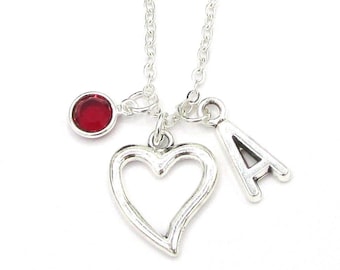 May include: A silver necklace with a heart charm, a letter A charm, and a red gemstone charm.