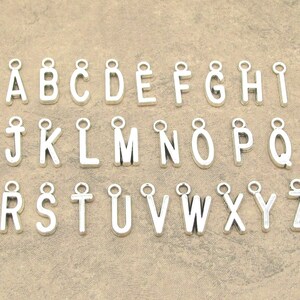 May include: A set of 26 silver charm pendants, each featuring a letter of the alphabet. The charms are ideal for adding a personalised touch to jewellery projects.
