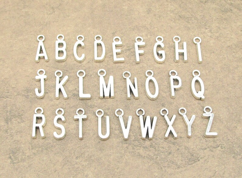 May include: A set of 26 silver charm pendants, each featuring a letter of the alphabet. The charms are ideal for adding a personalised touch to jewellery projects.