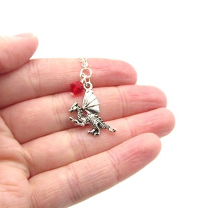 May include: Silver dragon pendant necklace with a red crystal charm. The dragon is in flight with its wings spread.