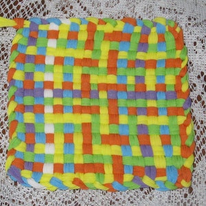 May include: A colorful woven pot holder with a yellow, orange, green, blue, and purple pattern. The pot holder has a loop for hanging.