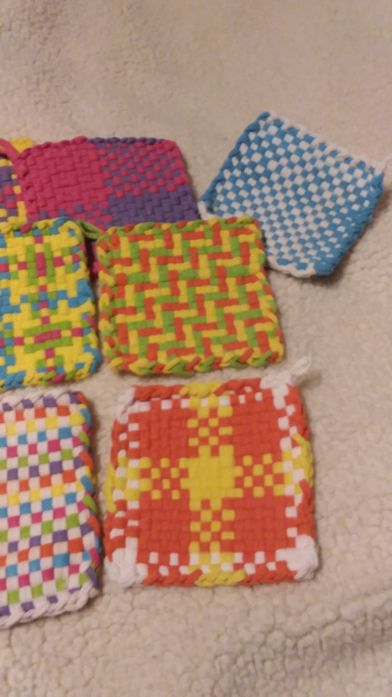 May include: A set of six colorful woven pot holders with different patterns. The pot holders are made with a variety of colors, including pink, purple, yellow, green, blue, orange, and white.