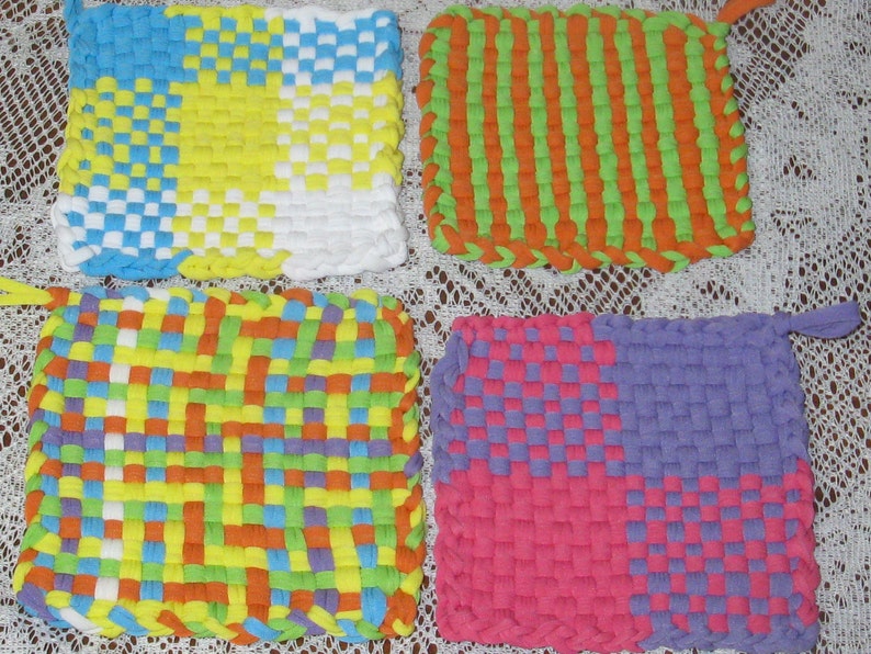 May include: Four colorful woven pot holders, each with a different pattern. The pot holders are made with a variety of colors, including blue, yellow, green, orange, purple, and pink.