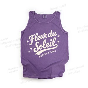 May include: A purple vest top featuring the text "Fleur du Soleil" in a white, stylized font. The text is accompanied by starburst graphics and the words "Mockup Studio" below. The vest top is made of a soft material.