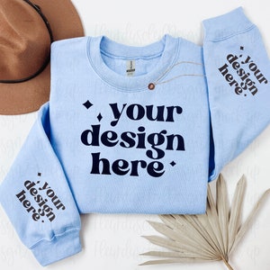 May include: A light blue sweatshirt with the text "your design here" printed in black on the front and sleeves.