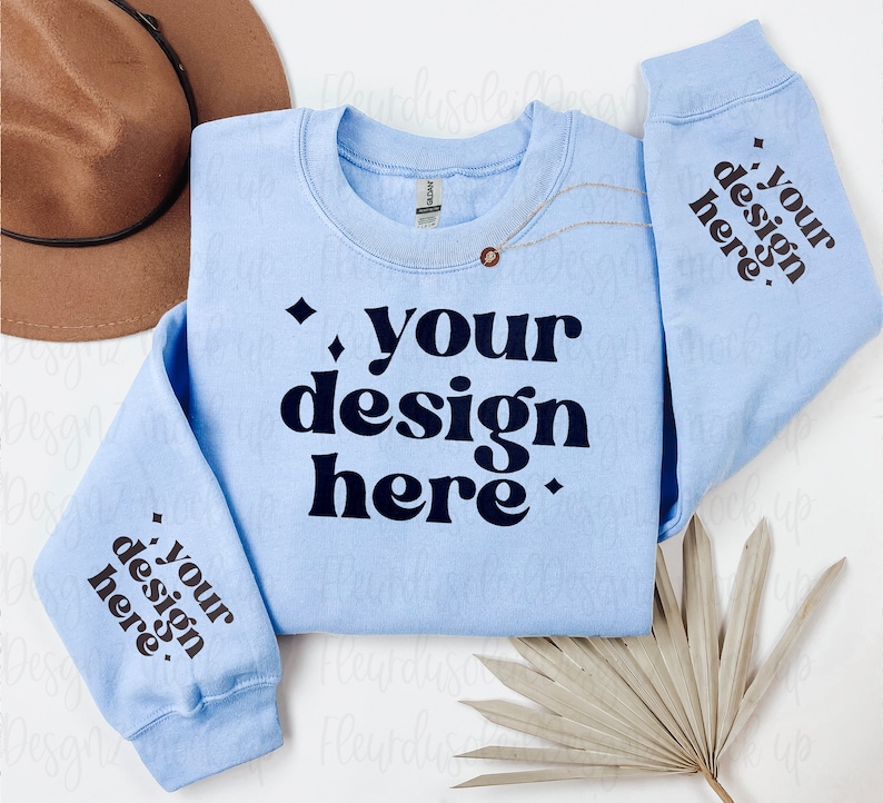May include: A light blue sweatshirt with the text "your design here" printed in black on the front and sleeves.