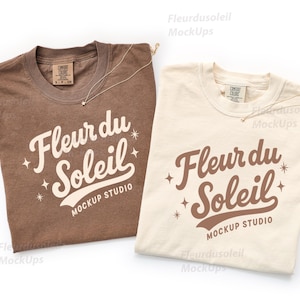 May include: Two t-shirts, one brown and one cream, with the text "Fleur du Soleil" in a script font. Each shirt has a small gold necklace. The shirts are from Mockup Studio.