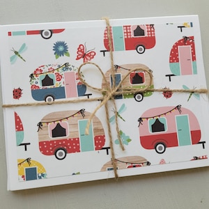 May include: A stack of white note cards with a repeating pattern of colorful vintage camper vans with floral, polka dot, and gingham designs. The cards are tied together with twine.