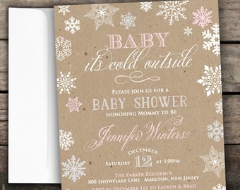 May include: A kraft paper baby shower invitation with pink and white snowflakes. The text reads "Baby it's cold outside" and includes details for a baby shower honoring Jennifer Winters on December 12th at 5:00 PM.