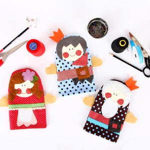May include: Three felt hand puppets, one with a red and white dress, one with a blue and white dress, and one with a brown and white dress. Each puppet has a crown and a smiling face.