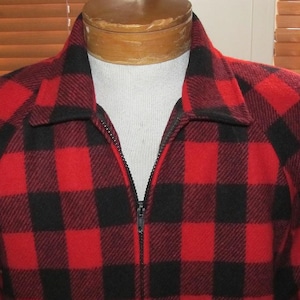 May include: A red and black plaid jacket with a zipper closure. The jacket is made of a soft, warm material.