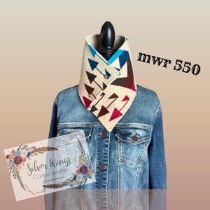 May include: A beige, brown, red, and blue patterned wool neck warmer with a snap closure. The neck warmer is on a mannequin wearing a denim jacket. The text "Silver Wings Custom Leather #montanamaker" is on a card in the lower left corner of the image. The text "mwr 550" is in the upper right corner of the image.