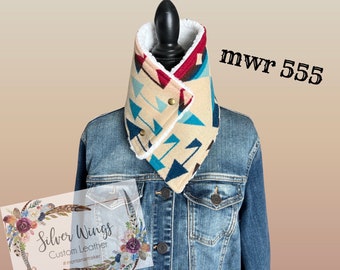 Könnte beinhalten: Ein beiger, blauer und roter gemusterter Fleece-Halswärmer mit weißem Sherpa-Futter. Der Halswärmer befindet sich auf einer Jeansjacke mit dem Text "Silver Wings Custom Leather #montanamaker" und "mwr 555" auf dem Bild.