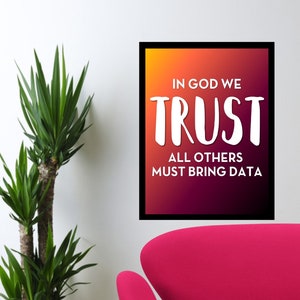 Può includere: Una stampa incorniciata con uno sfondo sfumato di arancione, giallo, rosso e viola. Il testo "In God We Trust" è in bianco, in grassetto e in un carattere grande. Sotto il testo c'è "All Others Must Bring Data" in bianco, in un carattere più piccolo.