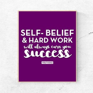 May include: A framed print with a purple background and white text that reads "SELF-BELIEF & HARD WORK will always earn you SUCCESS." The text is attributed to Virat Kohli. The frame is a light brown color.