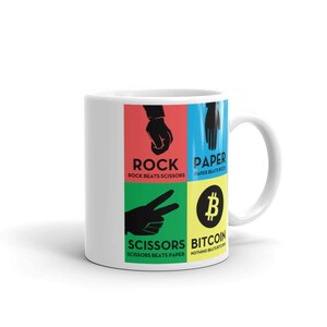 May include: White ceramic mug with a colourful design featuring the classic game of rock, paper, scissors, and a Bitcoin symbol. The text reads "Rock beats scissors", "Paper beats rock", "Scissors beats paper", and "Nothing beats Bitcoin".